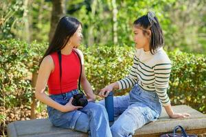 Calm Asian women chatting on bench during trip photo