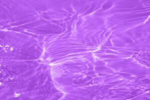 Purple water with ripples on the surface. Defocus blurred transparent blue colored clear calm water surface texture with splashes and bubbles. Water waves with shining pattern texture background. photo