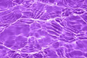 Purple water with ripples on the surface. Defocus blurred transparent blue colored clear calm water surface texture with splashes and bubbles. Water waves with shining pattern texture background. photo