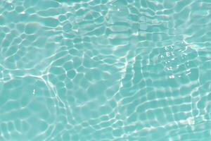 Blue water with ripples on the surface. Defocus blurred transparent blue colored clear calm water surface texture with splashes and bubbles. Water waves with shining pattern texture background. photo