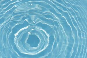 Blue water with ripples on the surface. Defocus blurred transparent blue colored clear calm water surface texture with splashes and bubbles. Water waves with shining pattern texture background. photo