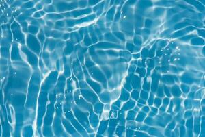 Blue water with ripples on the surface. Defocus blurred transparent blue colored clear calm water surface texture with splashes and bubbles. Water waves with shining pattern texture background. photo