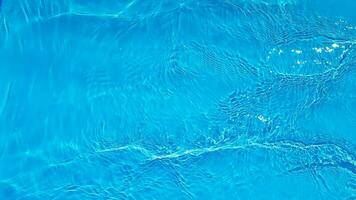 Blue water with ripples on the surface. Defocus blurred transparent blue colored clear calm water surface texture with splashes and bubbles. Water waves with shining pattern texture background. photo