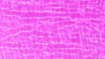 Purple water with ripples on the surface. Defocus blurred transparent pink colored clear calm water surface texture with splashes and bubbles. Water waves with shining pattern texture background. photo