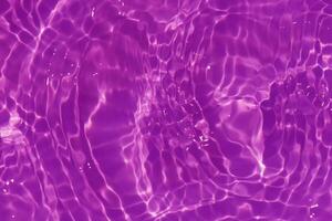 Purple water with ripples on the surface. Defocus blurred transparent pink colored clear calm water surface texture with splashes and bubbles. Water waves with shining pattern texture background. photo