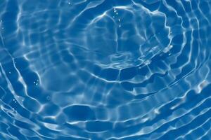 Blue water with ripples on the surface. Defocus blurred transparent blue colored clear calm water surface texture with splashes and bubbles. Water waves with shining pattern texture background. photo