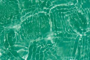 Blue water with ripples on the surface. Defocus blurred transparent blue colored clear calm water surface texture with splashes and bubbles. Water waves with shining pattern texture background. photo