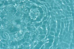 Blue water with ripples on the surface. Defocus blurred transparent blue colored clear calm water surface texture with splashes and bubbles. Water waves with shining pattern texture background. photo