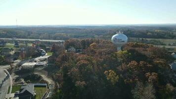 aéreo ver de eau clara, Wisconsin, agua torre y nuevo residencial barrio abajo. parque en otoño con brillante colores. video