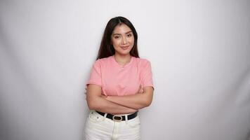 Confident smiling Asian woman dressed in pink, standing with arms folded and looking at the camera in Studio with White background video