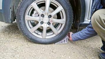 Person Platzierung Rad Keil unter Rad von bürgerlich Fahrzeug Reifen zu verhindern es ist Bewegung video