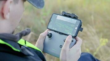 mãos de operador de drone usando controle remoto com varas e celular como monitor à luz do dia video