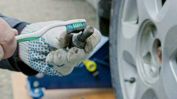 Hände von Mechaniker Reinigung Auto Rad Bolzen mit alt Zahn Bürste video