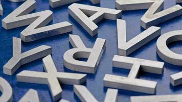 full frame close-up looped rotating background of silver metal letters on flat blue painted surface video