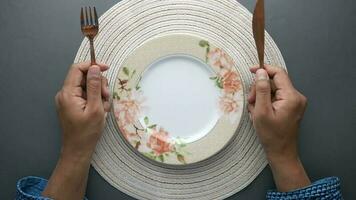 Hand holding cutlery with empty plate on wooden table video