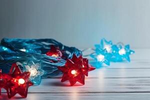 Christmas background with blue light luminous garlands and red stars on a white wooden background with copy space. photo