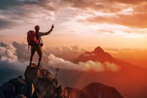 Successful hiker hiking a mountain pointing to the sunset. photo