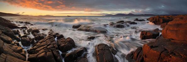 The waves are crashing over the rocks at sunset. photo