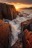 The waves are crashing over the rocks at sunset. photo