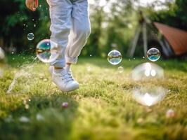 A close - up of big bubbles, blurred background of a child's legs wearing white clothes and running around on the lawn. photo