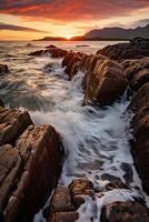 The waves are crashing over the rocks at sunset. photo