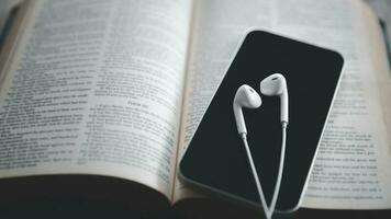 Christian online technology concept. Earphones over the holy bible with digital smartphone, Online live church for sunday service. Holy bible book and online study. photo