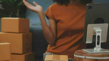 mujer joven dueña de una pequeña empresa comprando en línea en casa. tomando nota de los pedidos de los clientes con teléfonos móviles. pyme emprendedor o concepto de estilo de vida independiente. video