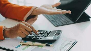 Close up Business woman using calculator and laptop for do math finance on wooden desk, tax, accounting, statistics and analytical research concept video