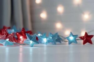 Christmas background with blue light luminous garlands and red stars on a white wooden background with copy space. photo