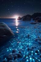 Ocean shore at night, the water is full of dinoflagellates, glowing with millions bright blue neon glow in the dark tiny dots. photo