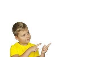 A boy in a yellow T-shirt on a white background points his fingers at something. The concept of a banner with information. Space for the text. photo