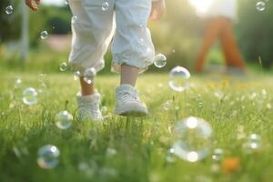 A close - up of big bubbles, blurred background of a child's legs wearing white clothes and running around on the lawn. photo