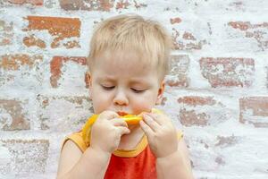 retrato de niño. linda chico posando con un naranja. el emociones de un niño. foto