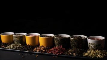Types of tea in a cup and leaves, healing tonic drink, black background isolate. . photo