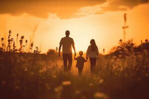 Silhouette of happy family walking in the meadow at sunset. photo