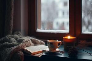 Christmas background. A cup of tea, books, a candle and a knitted scarf on the window background. photo