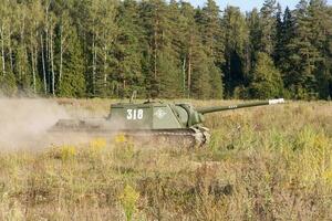 Moscow, Russia, 2018-08-25, exhibition of military equipment, display of military equipment in action. A military tank in motion against the background of green trees. photo