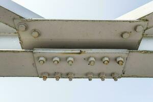 Bolts and nuts on metal plates of steel structure of heavy duty straight crossbar of frame and bridge support photo