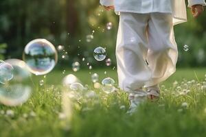 A close - up of big bubbles, blurred background of a child's legs wearing white clothes and running around on the lawn. photo