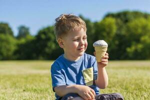 A happy boy is eating ice cream outdoors in the park. photo