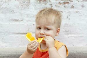 Portrait of child. Cute boy posing and eating a delicious orange. The emotions of a child. photo