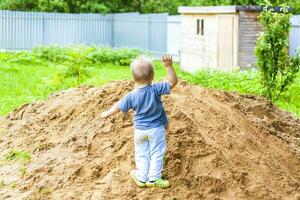 A little boy climbs a mountain with sand. The child is all dirty, but happy. photo