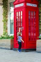 A little boy wants to enter a red phone booth. photo