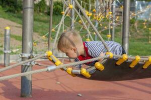 A little boy enthusiastically plays on the playground. Success, creative ideas and sports concepts. Children's playground. photo