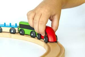 un niño obras de teatro con un tren hecho de madera. de cerca de un niño mano. foto