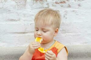 Portrait of child. Cute boy posing and eating a delicious orange. The emotions of a child. photo
