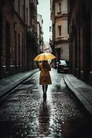 Yellow umbrella in hand of woman walking on a colorless street. photo