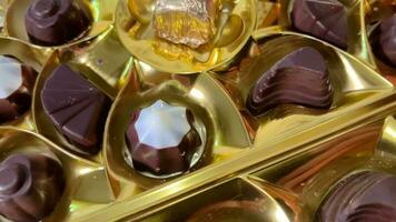 Chocolate candies of various shapes in a shiny golden package. video