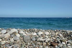 Bank of pebbles with the sea and beach in the background photo