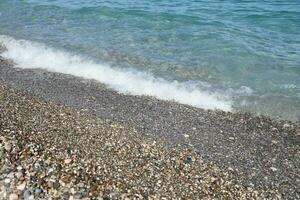 Bank of pebbles with the sea and beach in the background photo